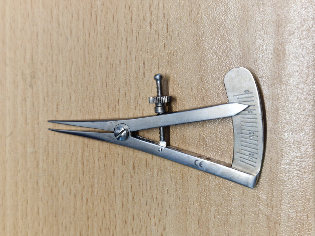 Castroviejo ophthalmic caliper showing adjustable screw and graduated millimetre scale