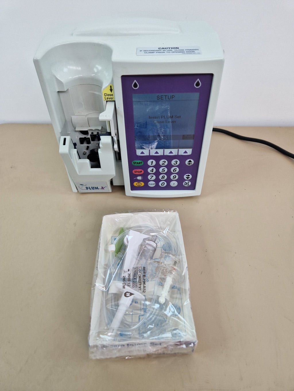Hospira Plum A+ infusion pump powered on with sample Hospira LifeCare pump set
