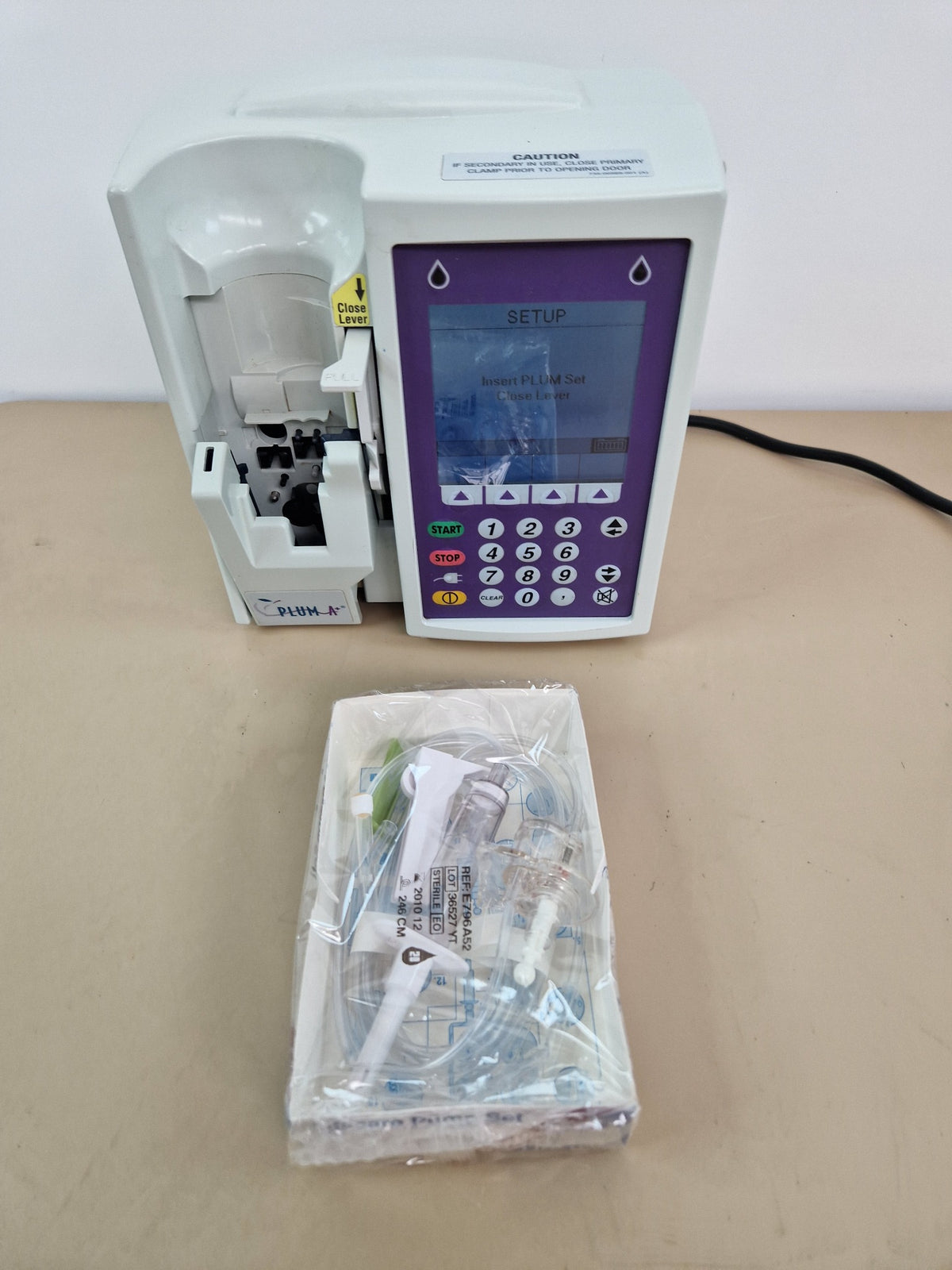 Hospira Plum A+ infusion pump powered on with sample Hospira LifeCare pump set