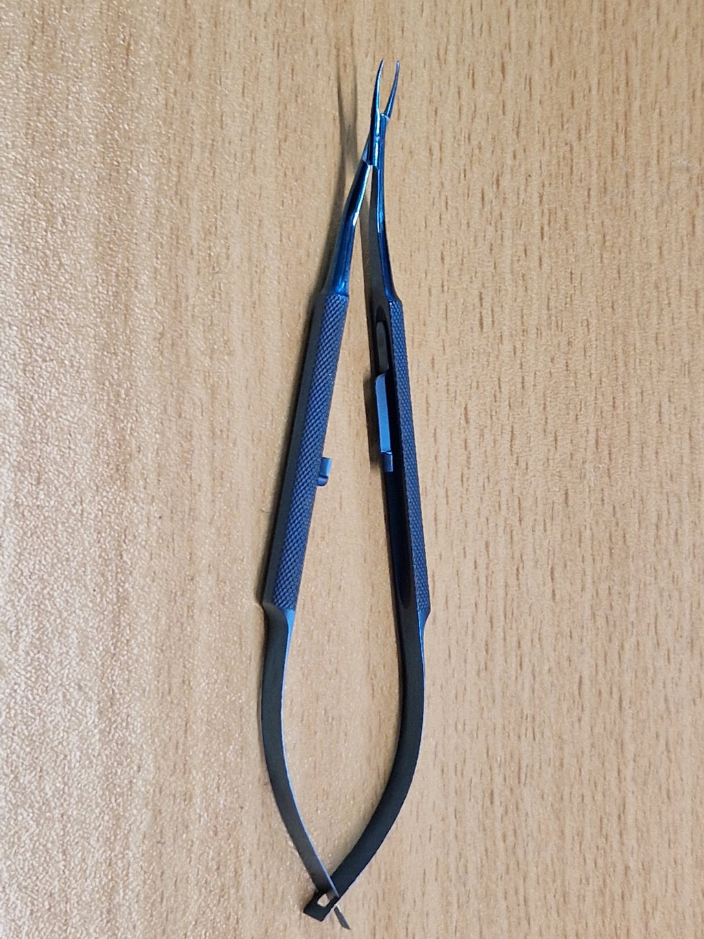 Close view of Castroviejo-style titanium micro needle holder showing straight jaws and locking catch