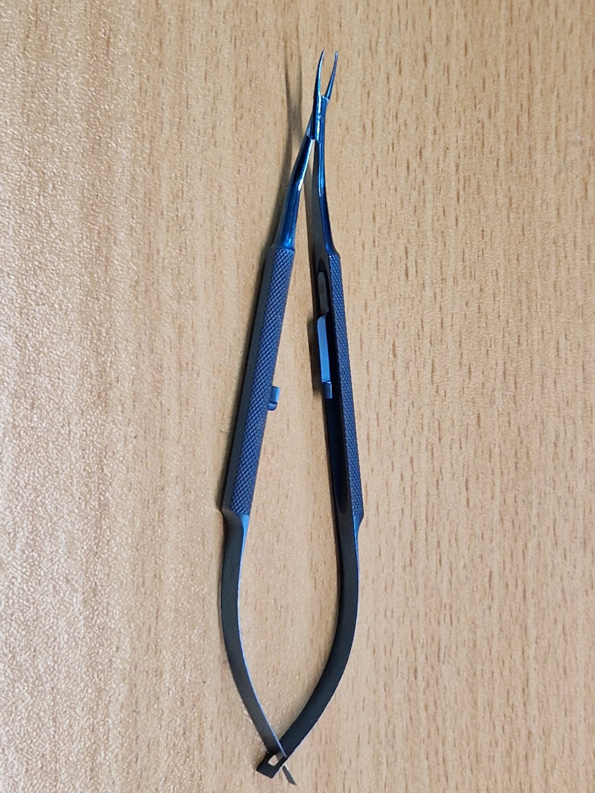 Close view of Castroviejo-style titanium micro needle holder showing straight jaws and locking catch
